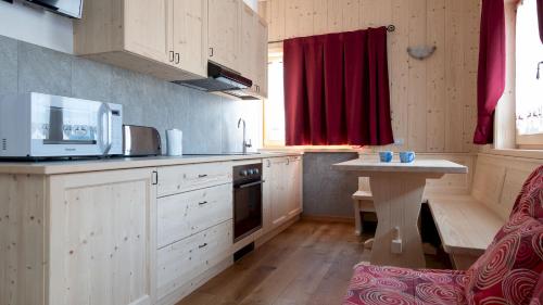 a kitchen with wooden cabinets and a table and a red curtain at Italianway - Ripa Fontana 1 Mono in Valdidentro