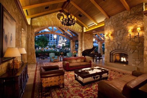 a living room with a stone fireplace and a piano at Gaylord Texan Resort and Convention Center in Grapevine