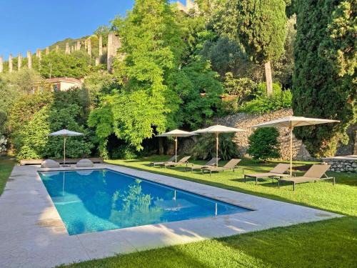 a swimming pool in a yard with umbrellas at 5 Terrazze Exlusive Apartments in Gargnano