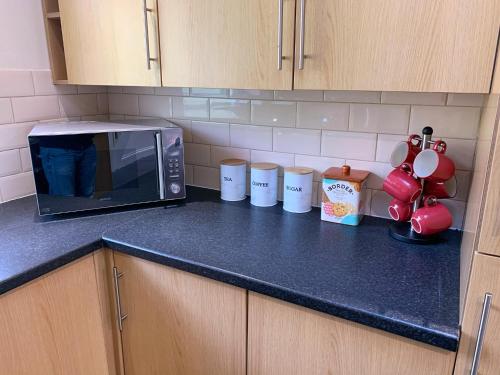 a kitchen counter with a microwave and cups on it at Yardley Lodge in Birmingham