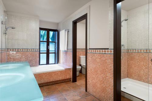 a bathroom with a tub and a toilet and a sink at Hotel Palacio del Carmen, Autograph Collection in Santiago de Compostela