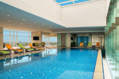 a large swimming pool in a hotel lobby with chairs at Four Points By Sheraton Kuwait in Kuwait