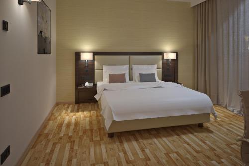 a bedroom with a large white bed and wooden floors at AC Hotel by Marriott Milan Sesto in Sesto San Giovanni