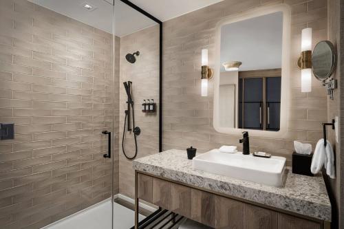 uma casa de banho com um lavatório, um chuveiro e um espelho. em The Otis Hotel Austin, Autograph Collection em Austin