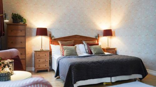 a bedroom with a bed with two night stands and two lamps at Hennickehammars Herrgård in Filipstad
