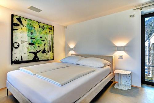a bedroom with a bed with a painting on the wall at 5 Terrazze Exlusive Apartments in Gargnano