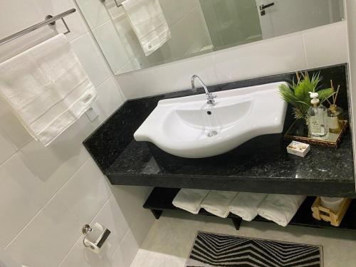 a bathroom with a white sink on a black counter at Apartamento em foz do Iguaçu in Foz do Iguaçu
