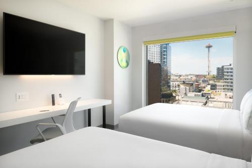a white hotel room with two beds and a desk and a window at Astra Hotel, Seattle, a Tribute Portfolio Hotel in Seattle
