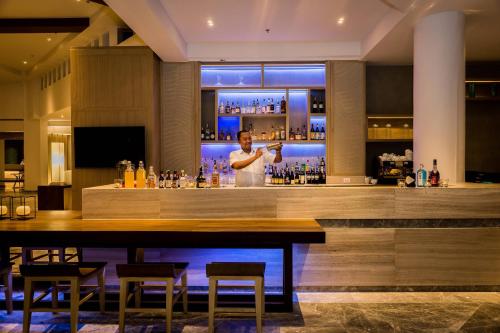 a man standing at a bar in a restaurant at Phuket Marriott Resort & Spa, Merlin Beach in Patong Beach