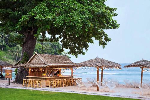 a bar on the beach with chairs and umbrellas at Phuket Marriott Resort & Spa, Merlin Beach in Patong Beach