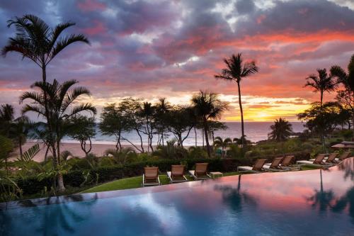 a pool with chairs and palm trees and a sunset at The Westin Hapuna Beach Resort in Hapuna Beach