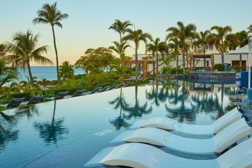 a pool at a resort with chairs and palm trees at The Westin Hapuna Beach Resort in Hapuna Beach
