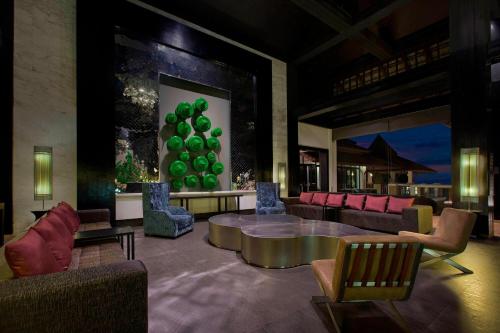a lobby with couches and a table with green balls on the wall at Le Meridien Chiang Rai Resort, Thailand in Chiang Rai
