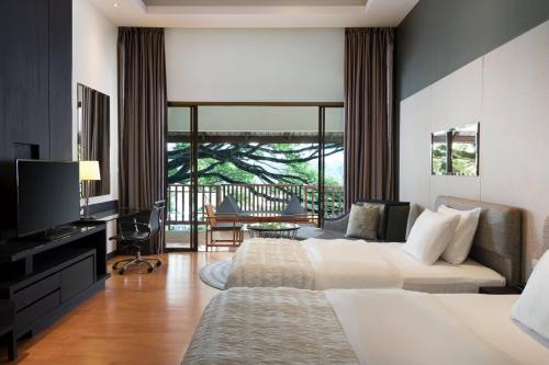 a hotel room with two beds and a television at Le Meridien Chiang Rai Resort, Thailand in Chiang Rai