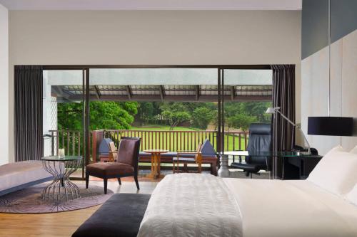 a bedroom with a bed and a living room at Le Meridien Chiang Rai Resort, Thailand in Chiang Rai