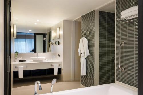 a bathroom with a tub and a sink and a mirror at Le Meridien Chiang Rai Resort, Thailand in Chiang Rai
