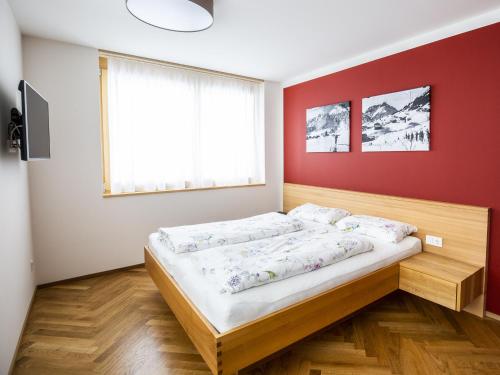 Bett in einem Zimmer mit roter Wand in der Unterkunft Chalet Alpenluft in Hirschegg