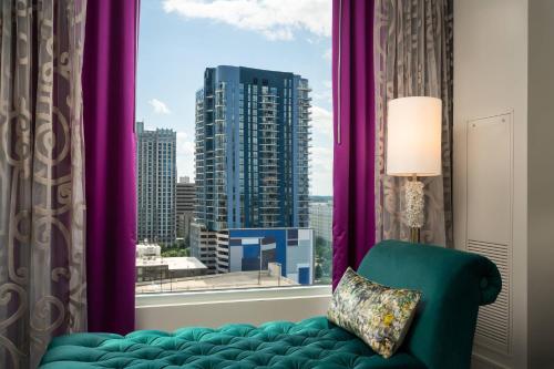シャーロットにあるGrand Bohemian Hotel Charlotte, Autograph Collectionの緑の椅子、紫のカーテン付きの窓が備わる客室です。