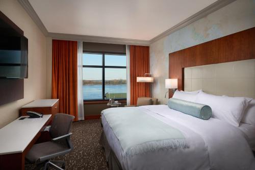 een hotelkamer met een groot bed en een bureau bij The Merrill Hotel & Conference Center, Muscatine, a Tribute Portfolio Hotel in Muscatine