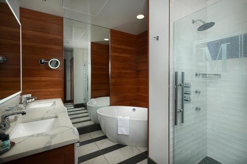 bagno con vasca, lavandino e doccia di The Merrill Hotel & Conference Center, Muscatine, a Tribute Portfolio Hotel a Muscatine