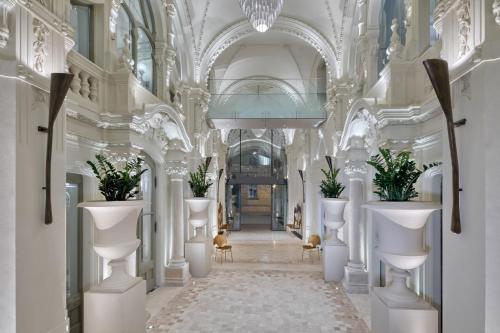 a hallway with white columns and plants in a building at Matild Palace, a Luxury Collection Hotel in Budapest