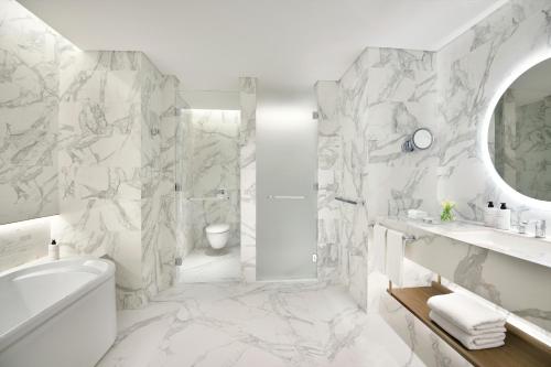 a white bathroom with a shower and a sink at InterContinental Residences Abu Dhabi, an IHG Hotel in Abu Dhabi