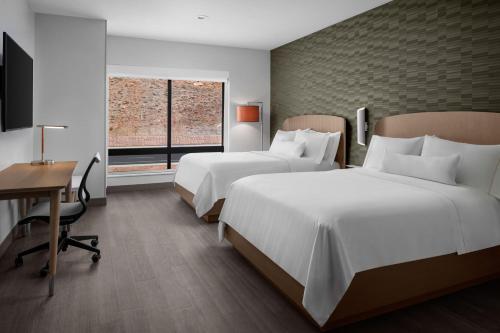 a hotel room with two beds and a desk and a window at Element Moab in Moab