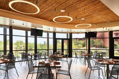 a dining room with tables and chairs and windows at Sheraton Grand at Wild Horse Pass in Chandler