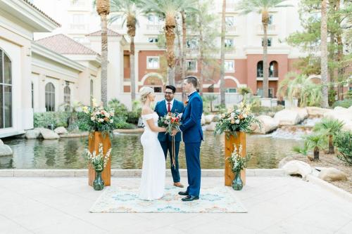 a bride and groom pose for a picture in front of a pond at JW Marriott Las Vegas Resort & Spa in Las Vegas