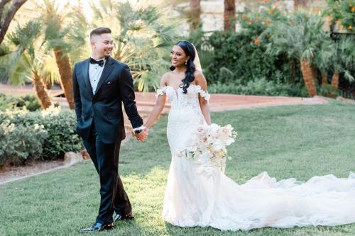 a bride and groom holding hands while walking on the grass at JW Marriott Las Vegas Resort & Spa in Las Vegas