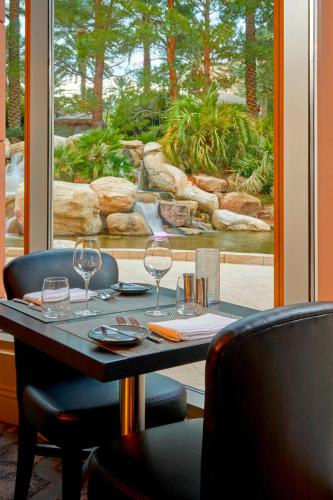 a table with wine glasses and a view of a waterfall at JW Marriott Las Vegas Resort & Spa in Las Vegas