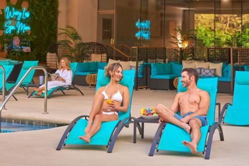 a man and a woman sitting on lounge chairs by a pool at JW Marriott Las Vegas Resort & Spa in Las Vegas