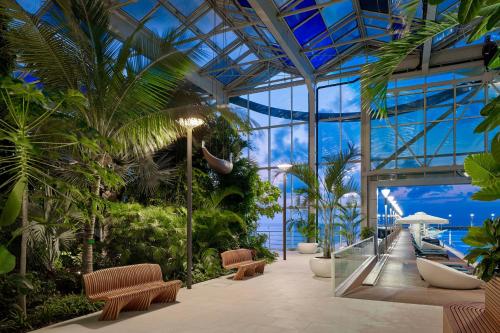 a glass building with benches and palm trees at Paragraph Resort & Spa Shekvetili, Autograph Collection in Shekvetili