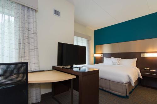 Residence Inn Raleigh-Durham Airport/Brier Creek في رالي: غرفة فندقية بسرير ومكتب مع تلفزيون