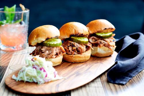 three pulled pork sandwiches on a cutting board with coleslaw at Renaissance Nashville Hotel in Nashville