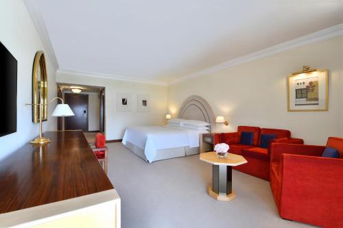 a hotel room with a bed and red furniture at Sheraton Grand Doha Resort & Convention Hotel in Doha