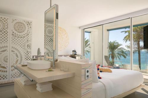 a white bathroom with a sink and a mirror at W Ibiza in Santa Eularia des Riu