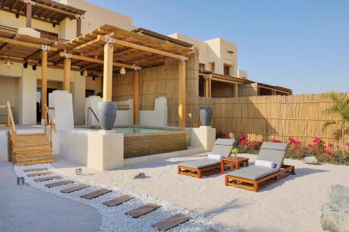 a patio with a pool and chairs and a house at Al Wathba, a Luxury Collection Desert Resort & Spa, Abu Dhabi in Abu Dhabi