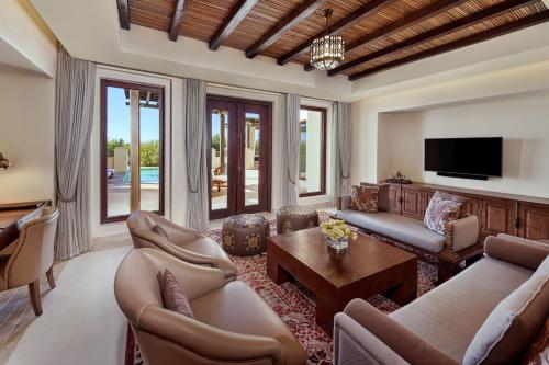 Al Wathba, a Luxury Collection Desert Resort & Spa, Abu Dhabi في أبوظبي: غرفة معيشة مع كنب وتلفزيون