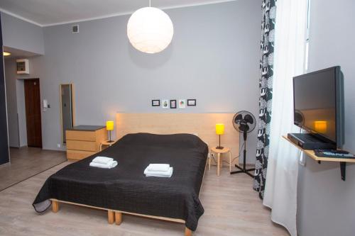 a bedroom with a black bed and a television at Apartamenty Sedinum in Szczecin