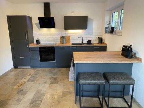 a kitchen with blue cabinets and a counter with stools at Ferienwohnung Bergblick Wangen im Allgäu mit Garten, 2022 komplett renoviert in Wangen im Allgäu