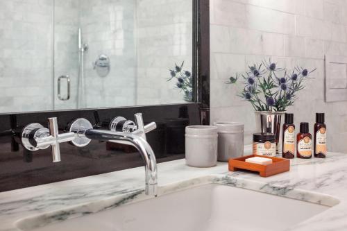 La salle de bains est pourvue d'un lavabo, d'un robinet et d'un miroir. dans l'établissement The Press Hotel, Autograph Collection, à Portland