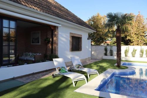 a backyard with two chairs and a swimming pool at La Casa de Enfrente in Herencia