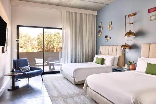 a hotel room with two beds and a chair at ADERO Scottsdale Resort, Autograph Collection in Scottsdale