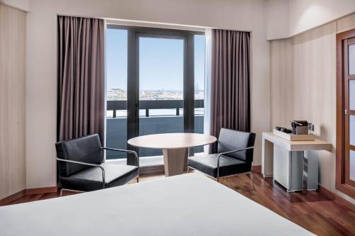 ein Hotelzimmer mit einem Tisch, Stühlen und einem Fenster in der Unterkunft AC Hotel Gran Canaria by Marriott in Las Palmas de Gran Canaria