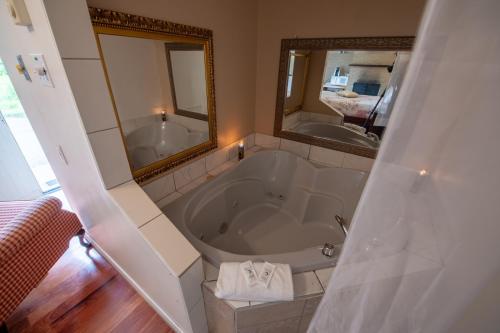 a bathroom with a tub and a large mirror at Motel Fleur de Lys in Magog-Orford