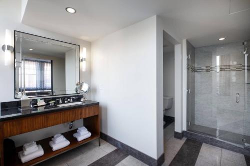 a bathroom with a shower and a sink and a mirror at Ambassador Hotel Wichita, Autograph Collection in Wichita