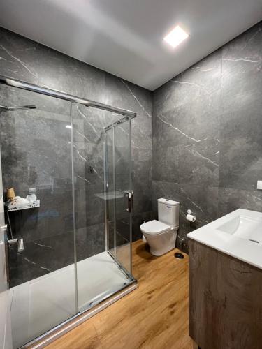 Un baño con ducha, inodoro y lavabo. en Costa Santander. Apartamento con jardín, en Santander