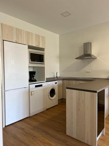La cuisine est équipée d'un réfrigérateur blanc et d'un lave-vaisselle. dans l'établissement Costa Santander. Apartamento con jardín, à Santander