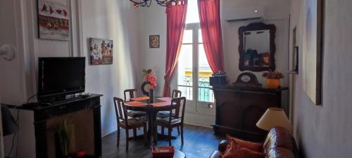 een woonkamer met een tafel en een raam bij Au QUATRE, 2em étage centre historique in Pézenas